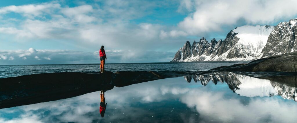 Woman standing on path looking at ocean and mountains